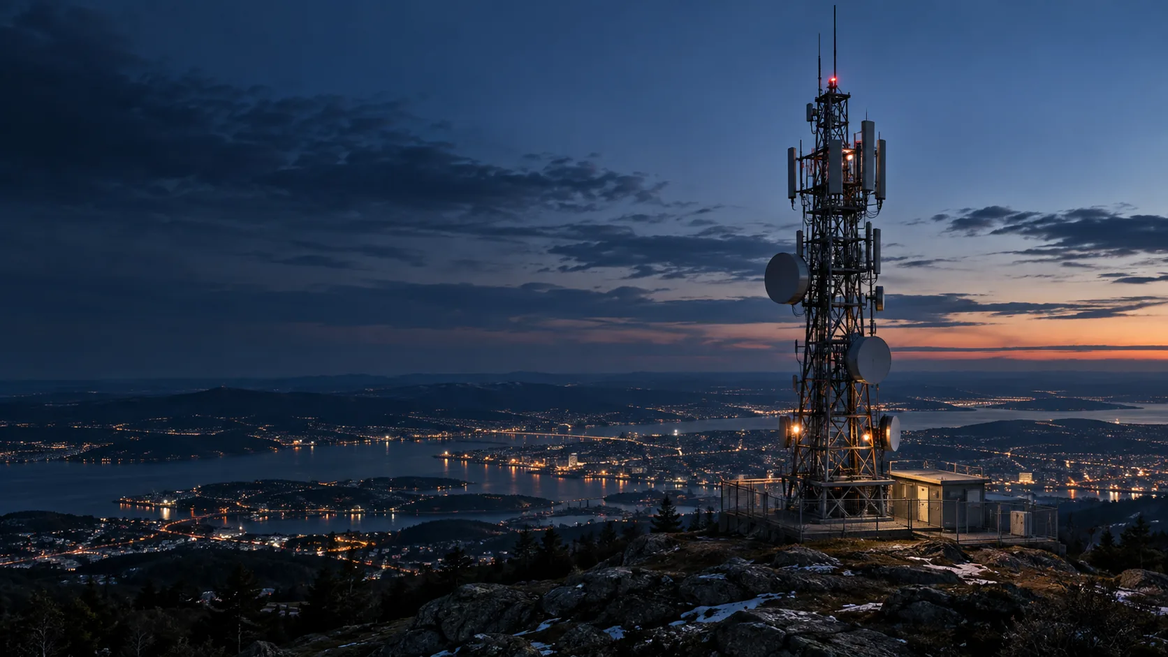 Illustrative telecommunications tower on a ridge overlooking a city at blue hour